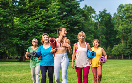 Multiethnic group of senior women training at park with fitness instructor - Active elderly people...