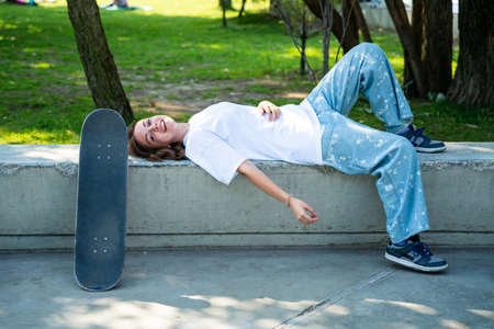 Young teenager at the skatepark. Professional skateboarder taking a break after exhibitionの写真素材