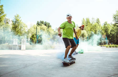 skaters with colored smoke bombs. Professional skateboarders having fun at the skate parkの写真素材