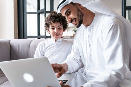 happy family spending time together. Arabian father and his son studying together on the computer