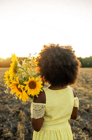 Pretty afro american girl in a sunflowers field having funの写真素材