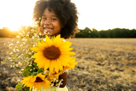 Pretty afro american girl in a sunflowers field having funの写真素材