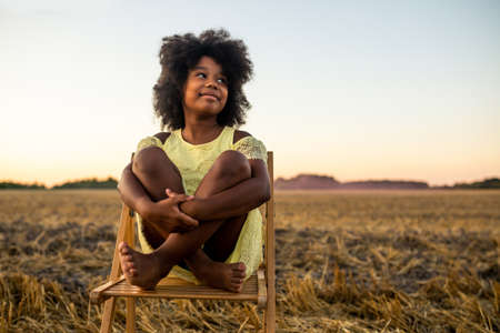 Pretty afro american girl in a sunflowers field having funの写真素材