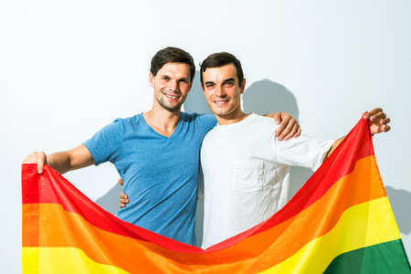 Lgbt family, gay couple holding a rainbow flagの写真素材