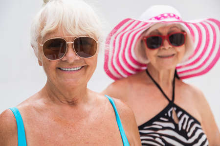 Happy senior women having party in the swimming pool - Elderly friends relaxing at a pool party