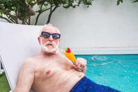 Happy senior man having party in the swimming pool - Active elderly male person sunbathing and...