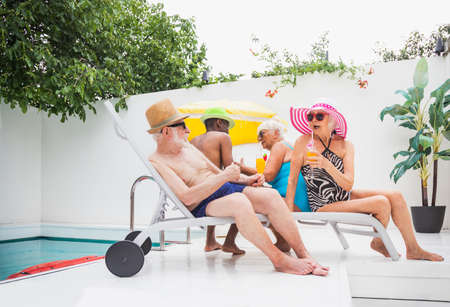 Happy seniors having party in the swimming pool - Elderly friends at a pool party during summertimeの写真素材