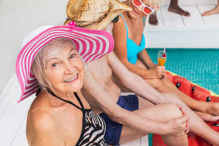 Happy seniors having party in the swimming pool - Elderly friends at a pool party during summertimeの写真素材