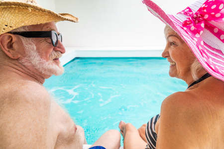 Happy senior couple having party in the swimming pool - Elderly friends releaxing at a pool party during summer vacationの写真素材