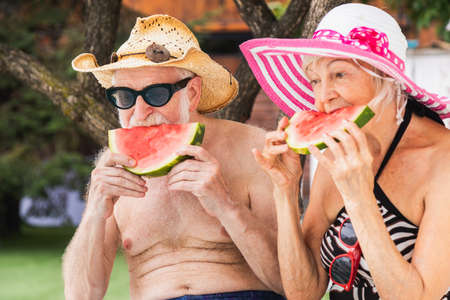 Happy senior couple having party in the swimming pool - Elderly friends releaxing at a pool party during summer vacationの写真素材