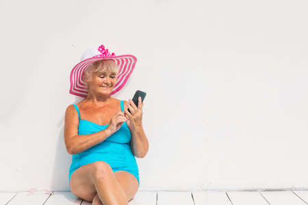 Happy senior woman having party in the swimming pool - Beautiful senior lady sunbathing and relaxing in a private pool during summertimeの写真素材