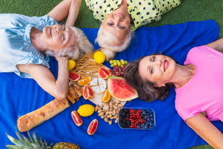 Beautiful senior women relaxing at home in the garden - Three pretty mature ladies rest in a peaceful backyard gardenの写真素材