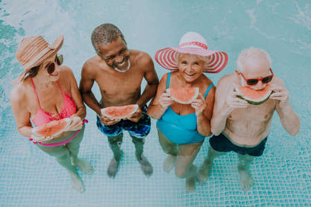Happy seniors having party in the swimming pool - Elderly friends at a pool party during summertimeの写真素材