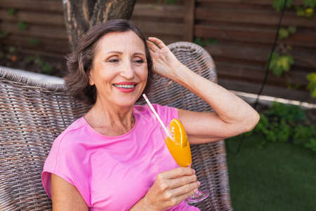 Beautiful senior woman relaxing at home in the garden - Pretty mature lady rests in a peaceful backyard gardenの写真素材