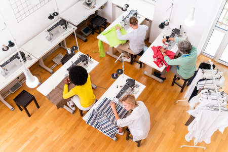 Multiethnic team of fashion designers working in a clothing start-up workshop - Multiracial group of...
