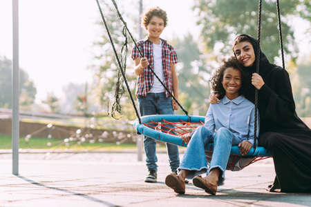 Cinematic image of a woman from the emirates with her children having fun at the playgroundの写真素材