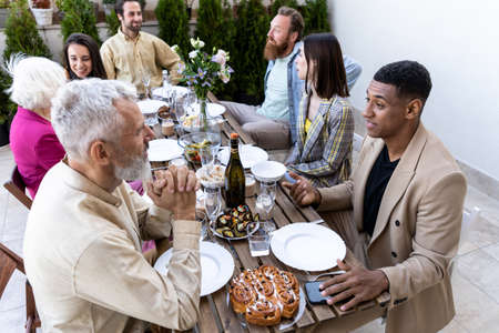 Storytelling footage of a multiethnic group of people dining on a rooftop. Family and friends make a reunion at homeの写真素材