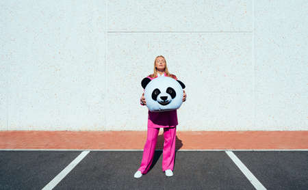 Young woman with a panda suit making party outdoorの写真素材