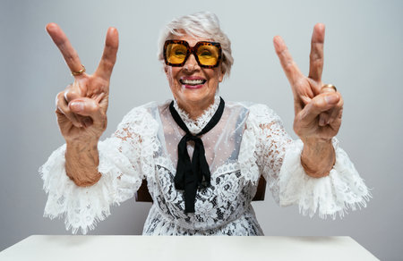beautiful and elegant old influencer woman. Cool grandmother posing in studio wearing fashionable clothes. Happy senior lady celebrating and making party. Concept about seniority and lifestyleの写真素材
