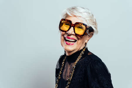 Beautiful and elegant old influencer woman. Cool grandmother posing in studio wearing fashionable...