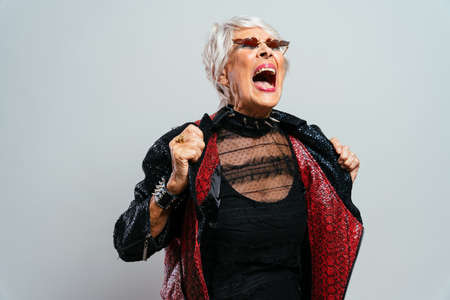 beautiful and elegant old influencer woman. Cool grandmother posing in studio wearing fashionable...