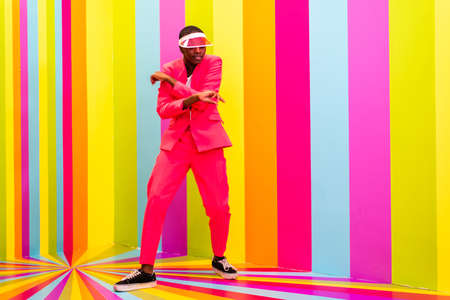 Beautiful african american young woman dancer having fun inside a rainbow box room - Cool and stylish afro adult woman portrait on multicolored background, influencer creating content for social networks in a selfie roomの写真素材