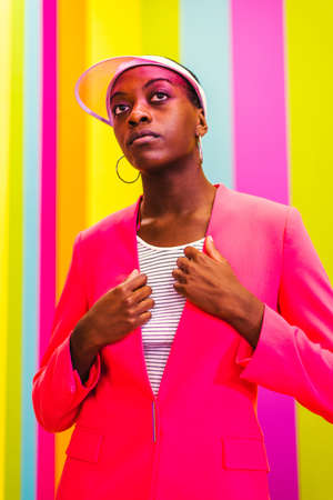 Beautiful african american young woman dancer having fun inside a rainbow box room - Cool and stylish afro adult woman portrait on multicolored background, influencer creating content for social networks in a selfie roomの写真素材