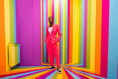 Beautiful african american young woman dancer having fun inside a rainbow box room - Cool and stylish afro adult woman portrait on multicolored background, influencer creating content for social networks in a selfie roomの写真素材