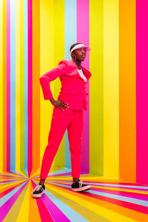 Beautiful african american young woman dancer having fun inside a rainbow box room - Cool and stylish afro adult woman portrait on multicolored background, influencer creating content for social networks in a selfie roomの写真素材