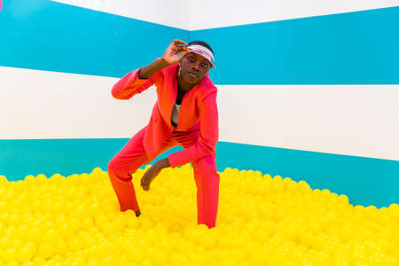 Beautiful african american young woman dancer having fun inside a rainbow box room - Cool and stylish afro adult woman portrait on multicolored background, influencer creating content for social networks in a selfie roomの写真素材