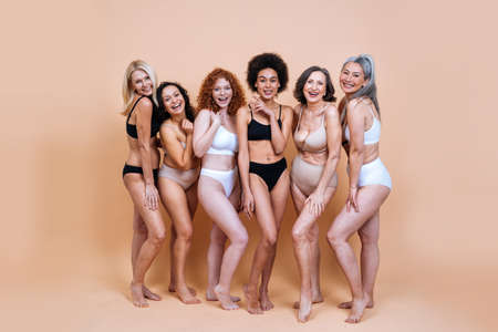 Beauty image of a group of women with different age, skin and body posing in studio for a body positive photoshooting. Mixed female models in lingerie on colored backgroundsの写真素材