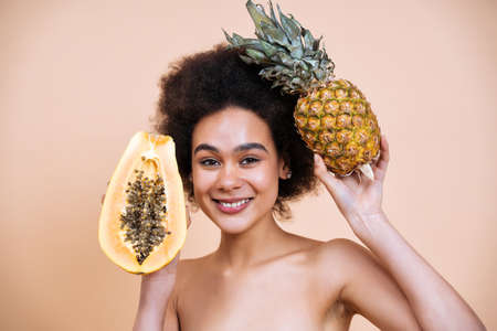 Image of a young woman posing in studio for a body positive concepts photoshooting. Teen model showing fruits and healthy food good for the skin care therapyの写真素材