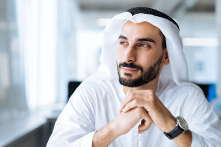 handsome man with dish dasha working in his business office of Dubai. Portraits of a successful...