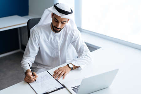 Handsome man with dish dasha working in his business office of Dubai. Portraits of a successful...