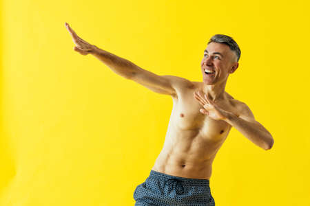 Handsome senior man posing in studio wearing beach trunks.の写真素材