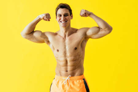 Handsome man posing in studio wearing beach trunks.