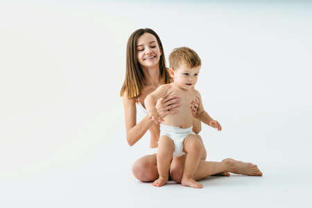 Happy woman holding her baby on colored background - Young woman wearing underwear taking care of her little son - Pregnancy, motherhood, people and expectation conceptの写真素材