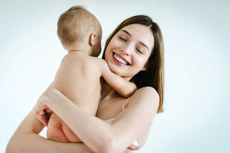 Happy woman holding her baby on colored background - Young woman wearing underwear taking care of her little son - Pregnancy, motherhood, people and expectation conceptの写真素材