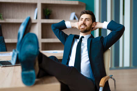 Businessman with elegant suit sitting at computer desk in the office - Adult man relax at work, concepts about business and technologyの写真素材
