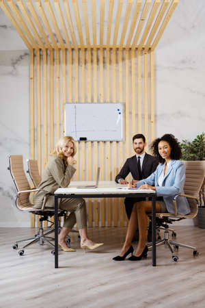 Multiracial group of businesspeople with elegant dress sitting at computer desk in the office - Diverse people working at laptop online in the meeting room, concepts about business and technologyの写真素材