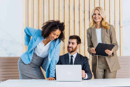 Multiracial group of businesspeople with elegant dress sitting at computer desk in the office -...