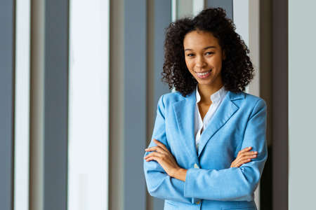 Beautiful adult businesswoman with elegant dress standing in a conference room - African american woman portrait in a business meeting, concepts about business and peopleの写真素材
