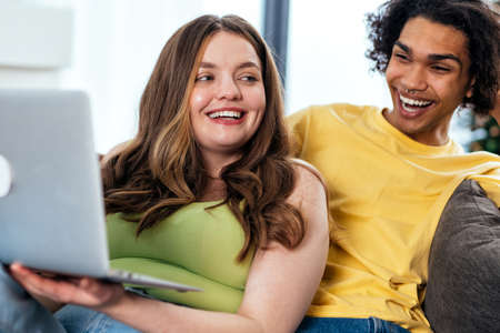 modern multiethnic unstereotyped couple watching series on the computer. Not stereotyped boyfriend...