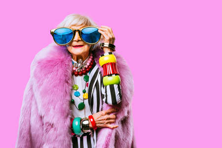 Happy and funny cool old lady with fashionable clothes portrait on colored background - Youthful grandmother with extravagant style, concepts about lifestyle, seniority and elderly peopleの写真素材