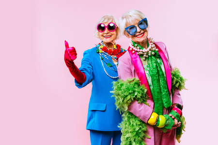 Happy and funny cool old ladies with fashionable clothes portrait on colored background - Youthful grandmothers with extravagant style, concepts about lifestyle, seniority and elderly peopleの写真素材