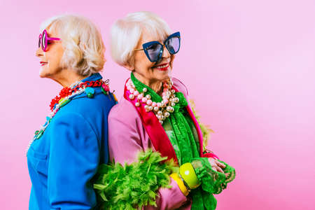 Happy and funny cool old ladies with fashionable clothes portrait on colored background - Youthful grandmothers with extravagant style, concepts about lifestyle, seniority and elderly peopleの写真素材