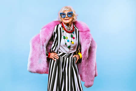 Happy and funny cool old lady with fashionable clothes portrait on colored background - Youthful...