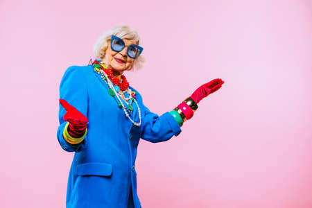 Happy and funny cool old lady with fashionable clothes portrait on colored background - Youthful grandmother with extravagant style, concepts about lifestyle, seniority and elderly peopleの写真素材
