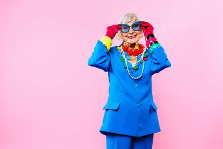 Happy and funny cool old lady with fashionable clothes portrait on colored background - Youthful grandmother with extravagant style, concepts about lifestyle, seniority and elderly peopleの写真素材