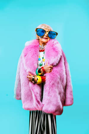Happy and funny cool old lady with fashionable clothes portrait on colored background - Youthful grandmother with extravagant style, concepts about lifestyle, seniority and elderly peopleの写真素材